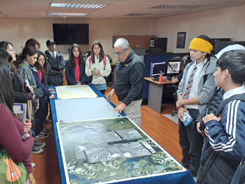 Profesional del SHOA, explicando cartografía sobre la mesa, a estudiantes de BETA PUCV. 
