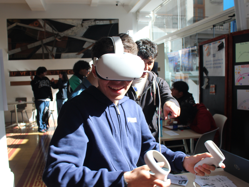 Estudiante con lentes 3D y monitores en sus manos, sonríe empleando la tecnología inmersiva. 